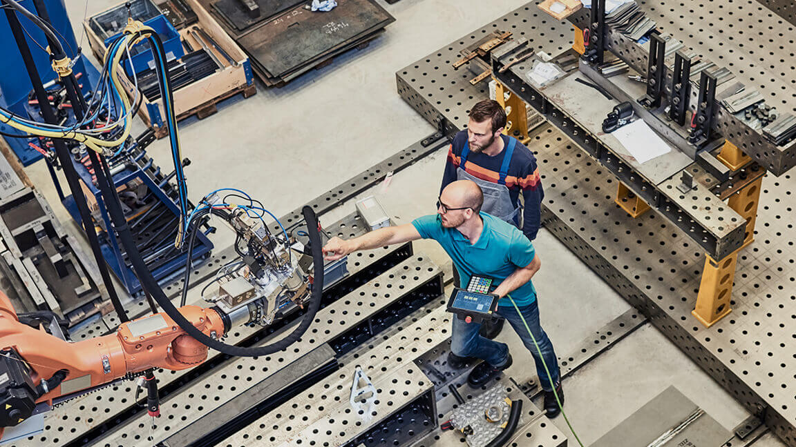 Two technicians working on a robot arm