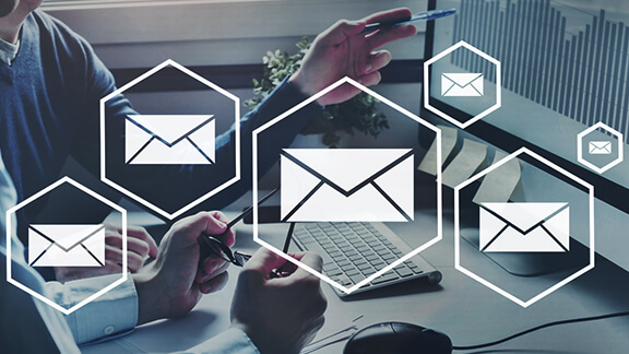 Envelopes in honeycombs in front of a photo with people on the computer.