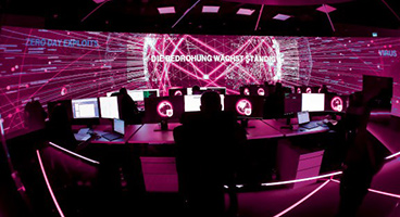 Magenta illuminated control room with warning message on big screen.