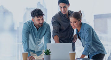 Two men and a woman standing in front of a laptop