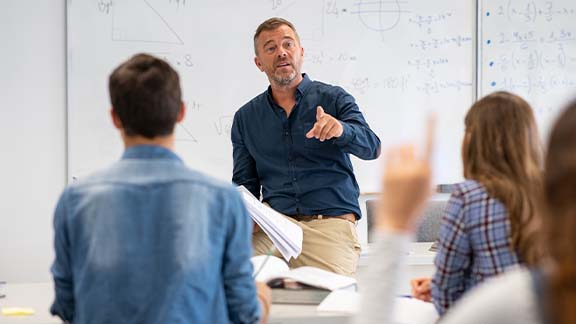 A man in a lecture hall teaching his pupils