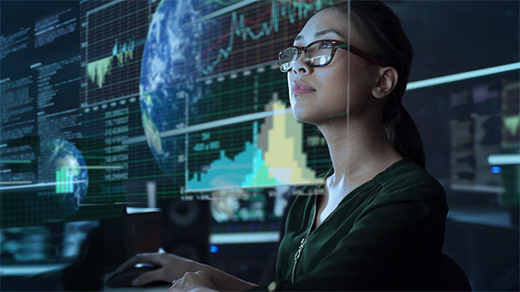 Woman working in front of several screens in a data center