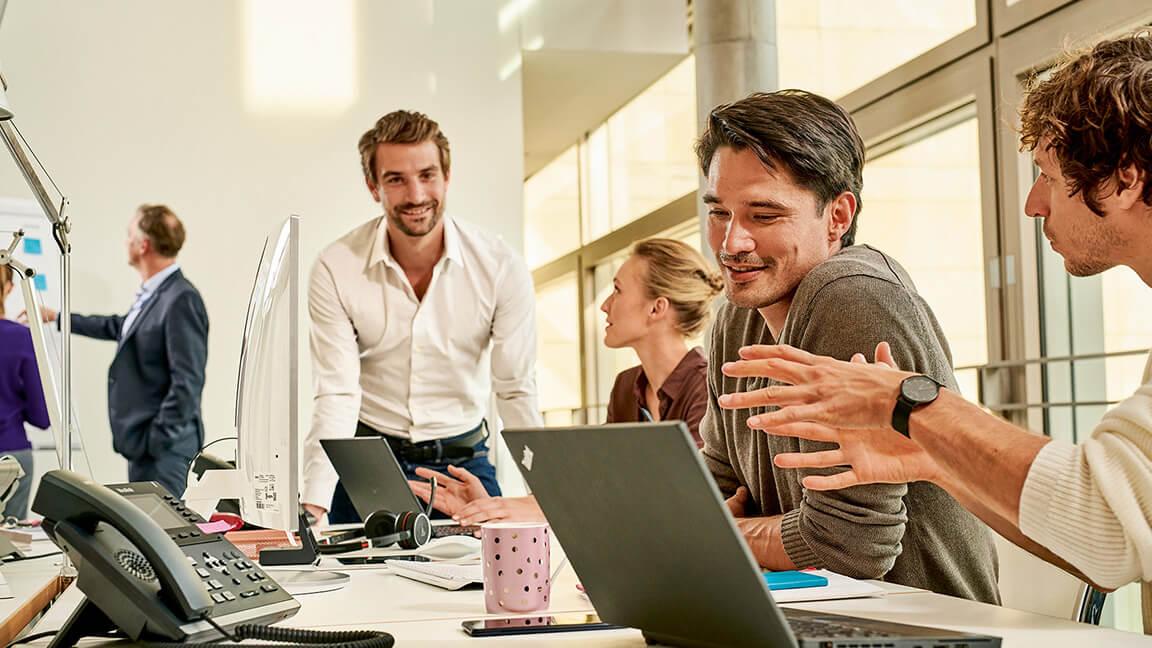 Mehrere jungs Menschen arbeiten zusammen an Laptops und Bildschirmen.