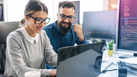 A woman and a man sitting at a laptop