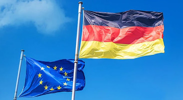 The European and German flags waving in the wind against a blue sky