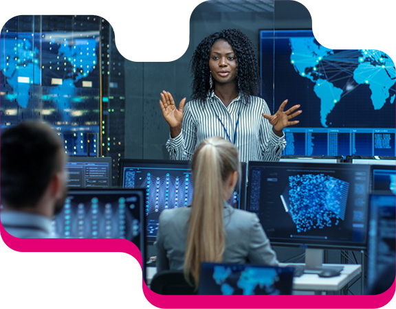 A woman in a control room talking to her colleagues.