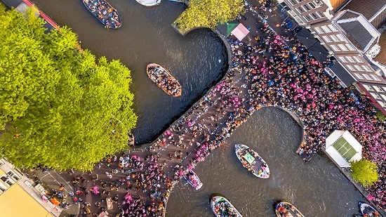 Crowd in magenta shirts on a T-shaped bridge photographed from above.