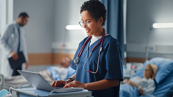 Ärztin unterhält sich mit Patientin und tippt auf Laptop