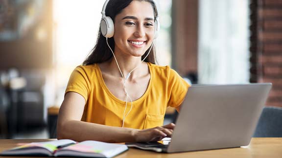 Lächelnde Frau am Laptop mit Kopfhörer