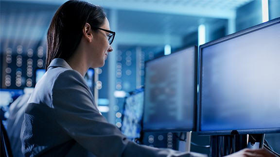 Woman with glasses sits in front of a screen