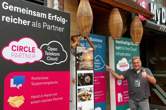 Mitarbeiter der Open Telekom Cloud vor Werbeaufstellern auf der Digital X