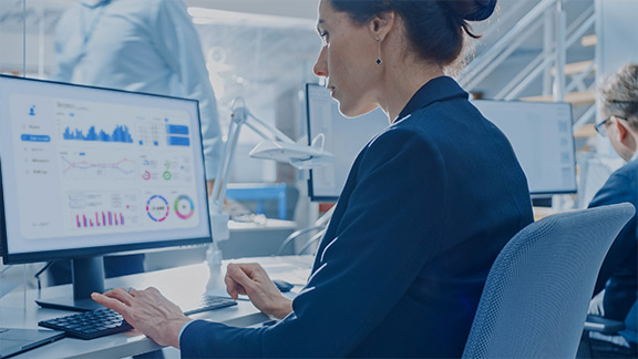 Woman sits in front of a laptop on the screen of which are displayed various data and diagrams