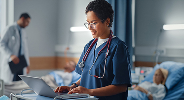 Doctor talking to patient and typing on laptop