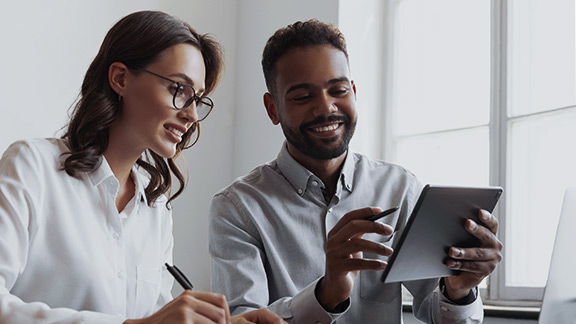 Two people in work clothes are looking at a tablet together