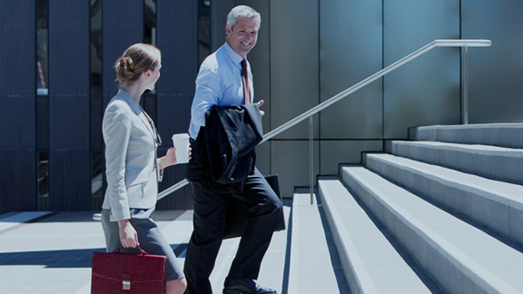 Two businessmen joyfully walk up stairs.