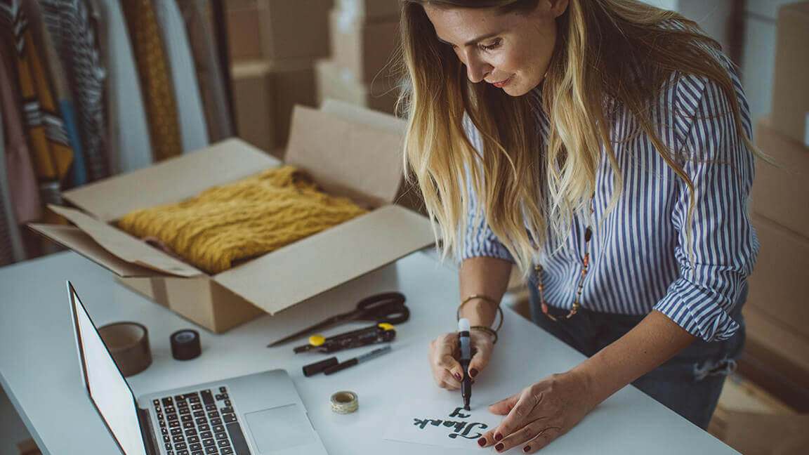 Woman standing in front of table with laptop