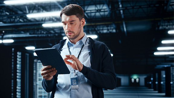 A man engages with his tablet inside a data center.