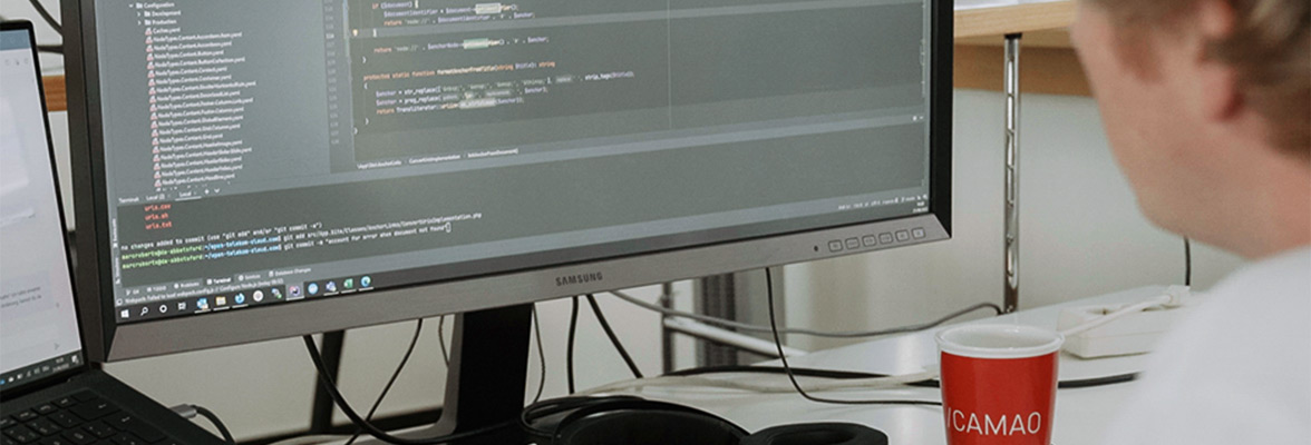 A man sits in front of a laptop and monitor